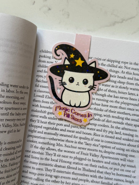 Cat-shaped sticker with a witch hat on an open book