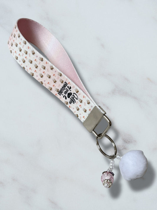 Keychain with pink strap and decorative elements on a light background