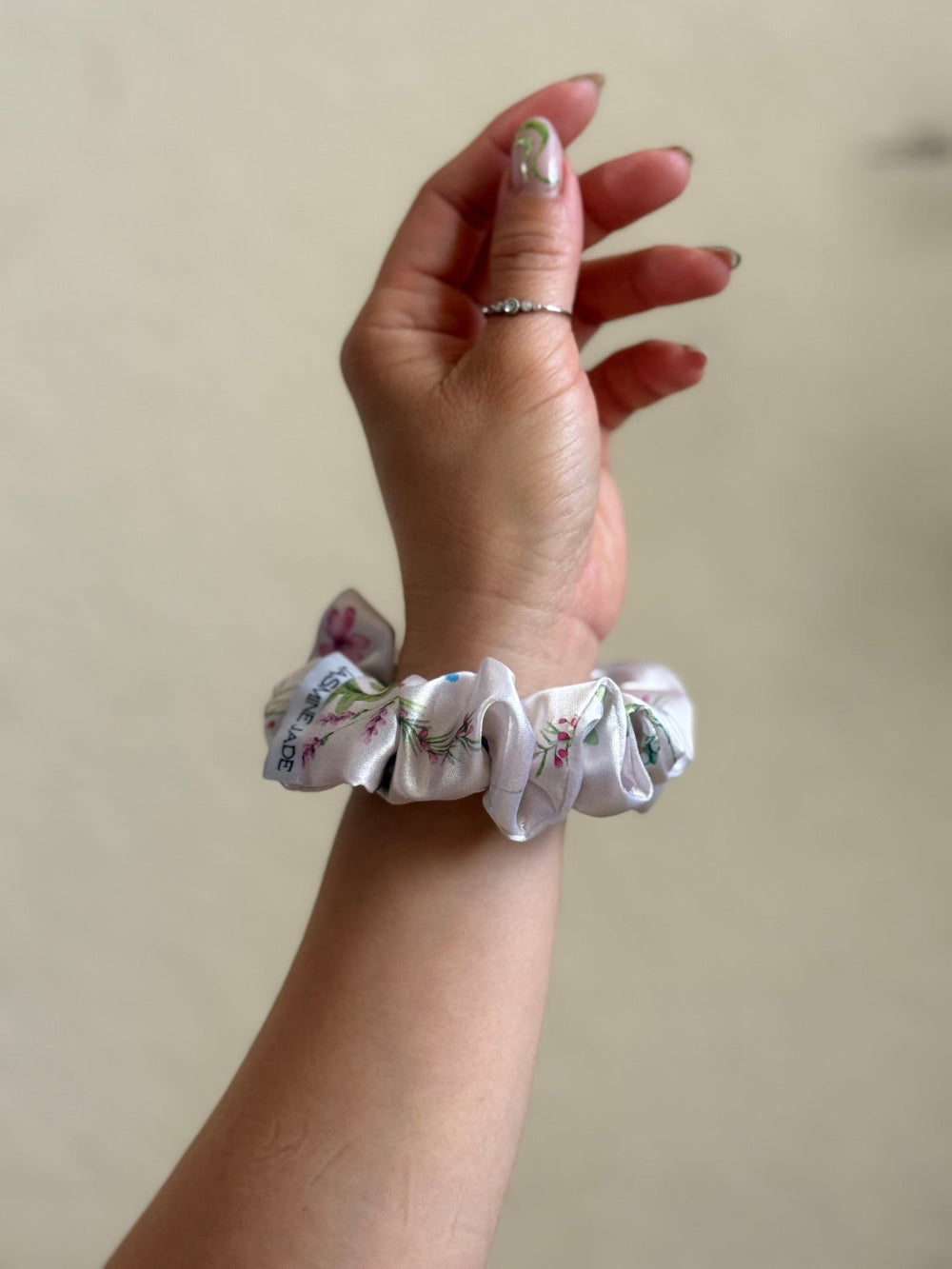 ivory satin floral scrunchie with delicate blue, pink, and green flowers on a neutral base, designed for every day wear, offering a secure and stylish hold.