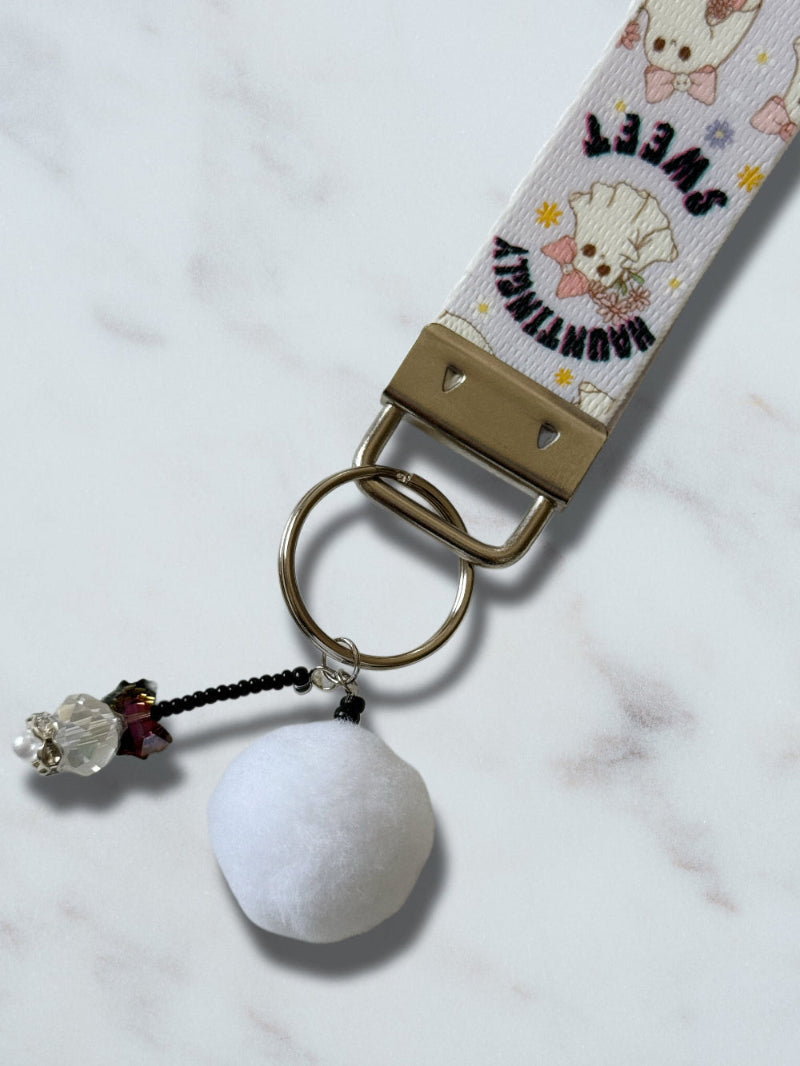 Keychain with white ball and decorative elements on a marble surface