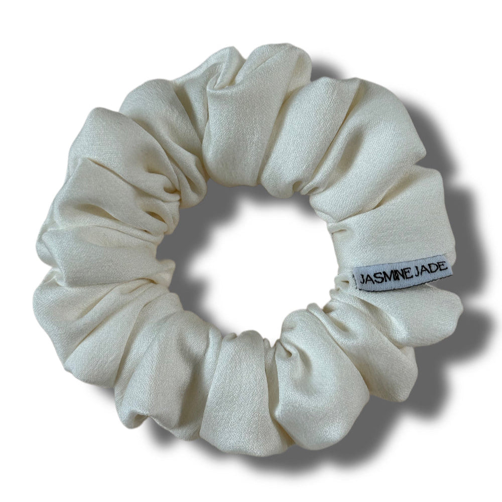 White scrunchie with a brand label on a white background