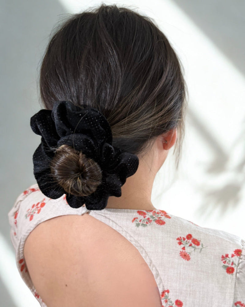 Person with a black floral hair accessory on a neutral background