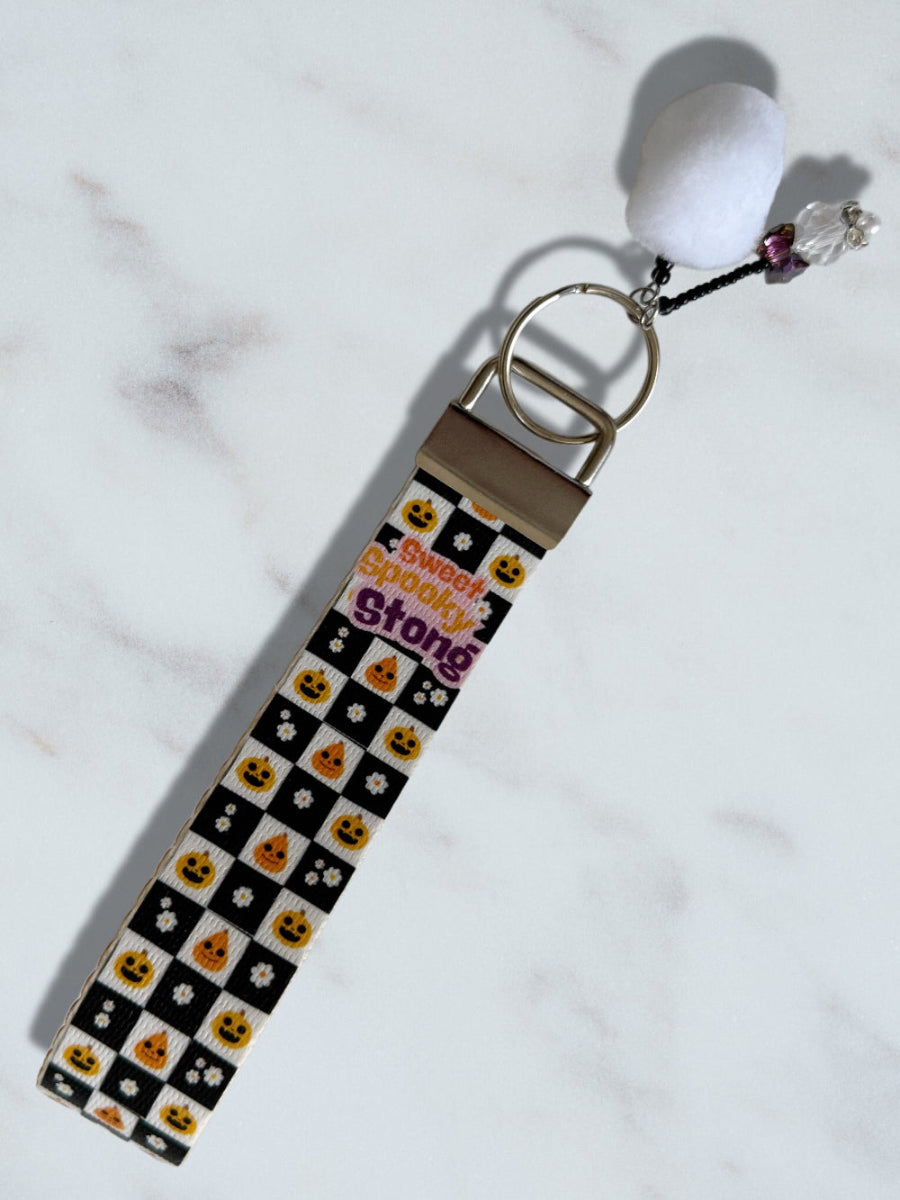 Keychain with checkered pattern and white ball charm on a light background
