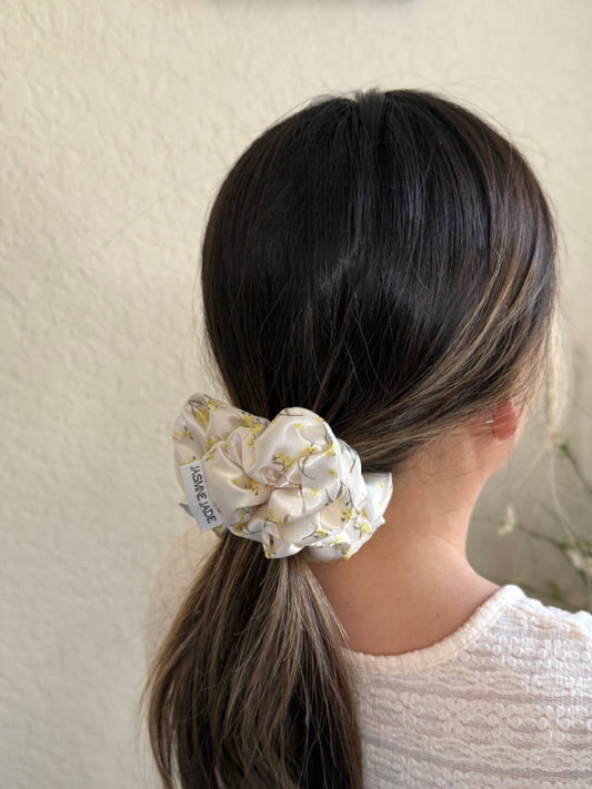 Person with a floral scrunchie in their hair against a neutral background