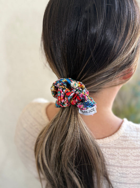 Scrunchie in a ponytail with a visible brand label against a neutral background