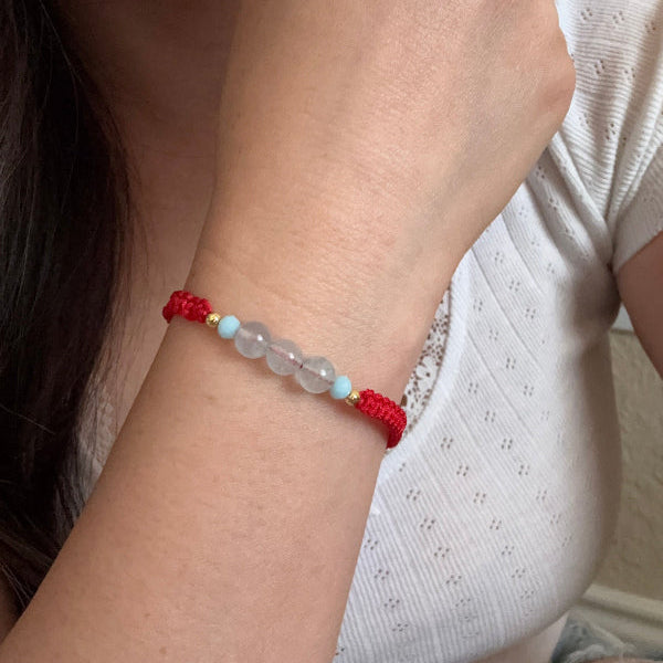 Close-up of a wrist wearing a red beaded bracelet with clear beads.