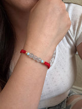 Close-up of a wrist wearing a red beaded bracelet with clear beads.