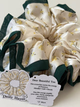 Set of floral scrunchies with a tag and branded card on a white background