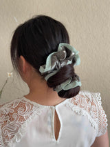Person wearing a light blue scrunchie in their hair against a neutral background