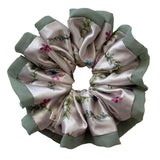 Floral patterned scrunchie with green trim on a light background