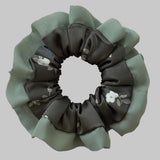 Green and gray scrunchie with floral design on a beige background