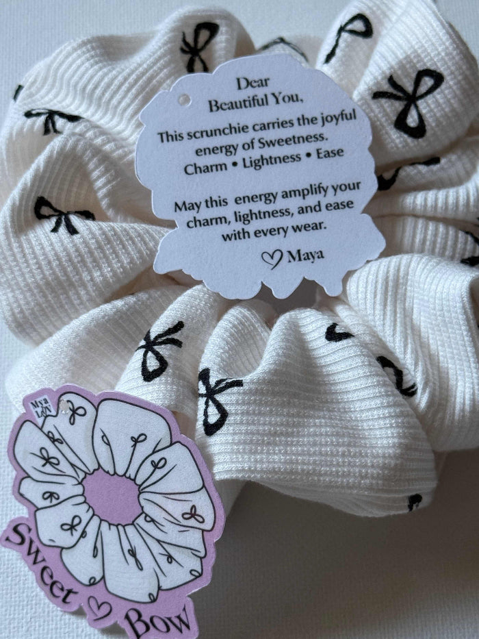 White scrunchies with black bows and a message tag on a white background
