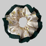 Floral patterned scrunchie with green trim on a light background