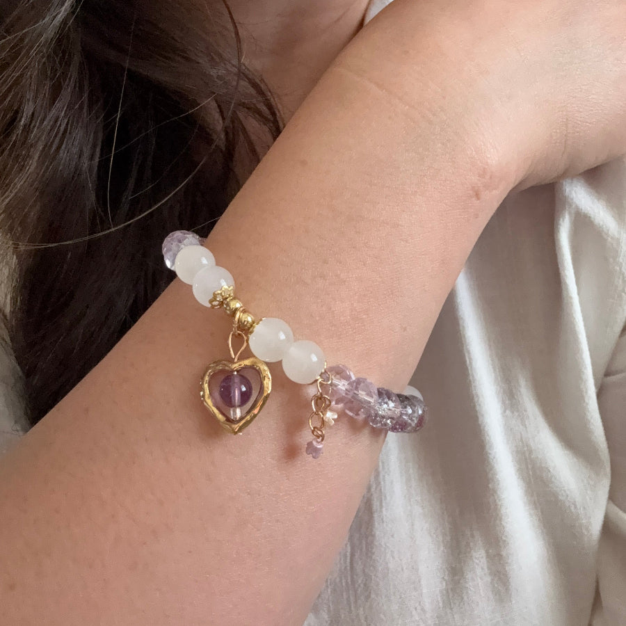 Close-up of a wrist wearing a beaded bracelet with a heart-shaped charm.