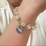 Bracelet with beads and a round charm on a wrist against a neutral background