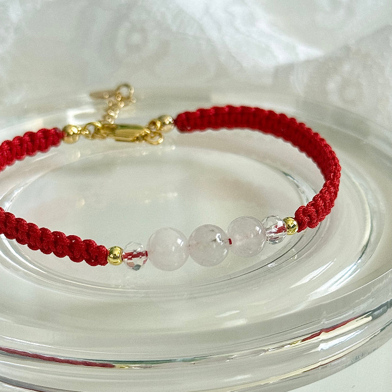 Red string bracelet with clear beads on a white background