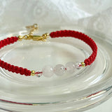 Red string bracelet with clear beads on a white background