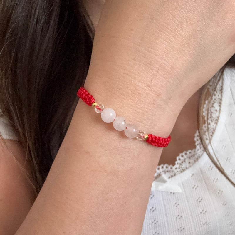 Close-up of a wrist wearing a red beaded bracelet with small white beads.