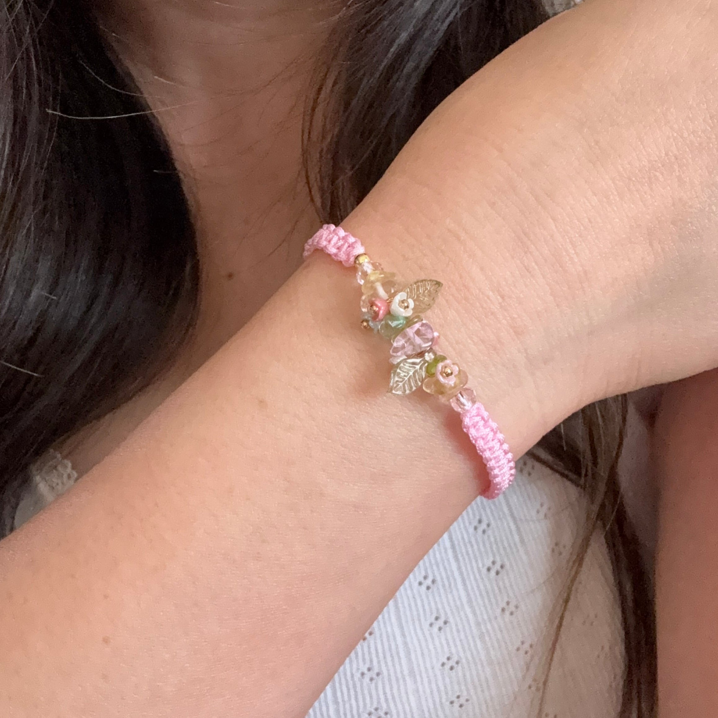 Close-up of a wrist wearing a pink bracelet with floral designs.