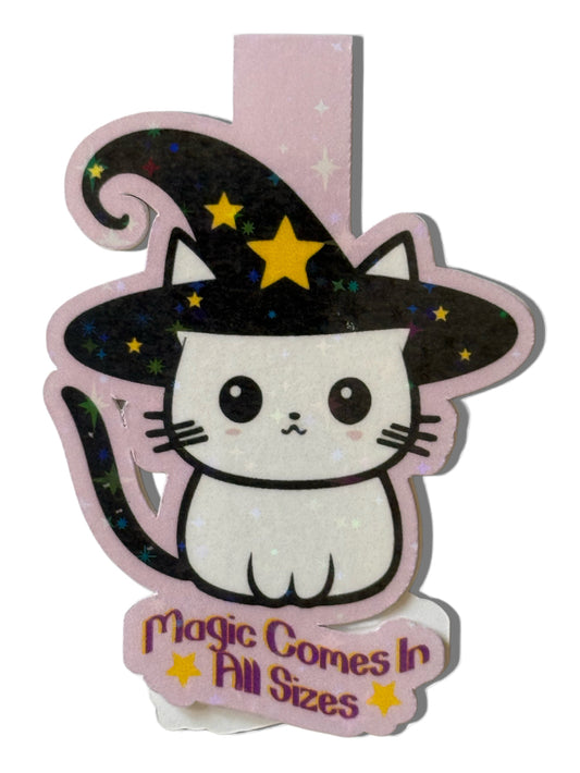 Cute cat in a witch hat with 'Magic Comes In All Sizes' text on a pink background