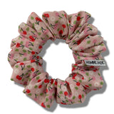 Pink scrunchie with cherry pattern on a white background