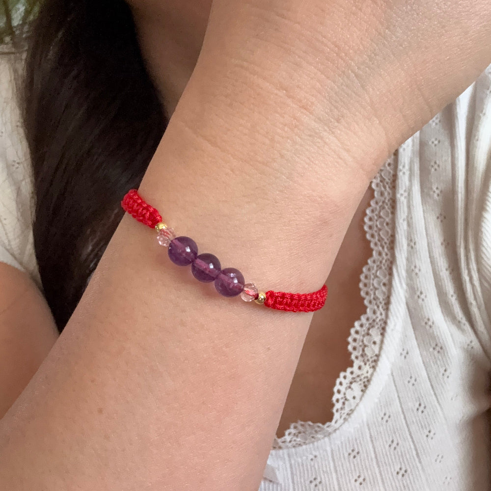 Close-up of a wrist wearing a red beaded bracelet with purple beads.