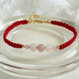 Bracelet with red cord and pink beads on a clear stand