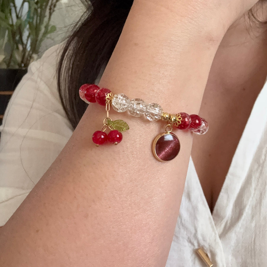 Close-up of a wrist wearing a decorative bracelet with red beads and gold accents.