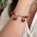 Close-up of a wrist wearing a decorative bracelet with red beads and gold accents.