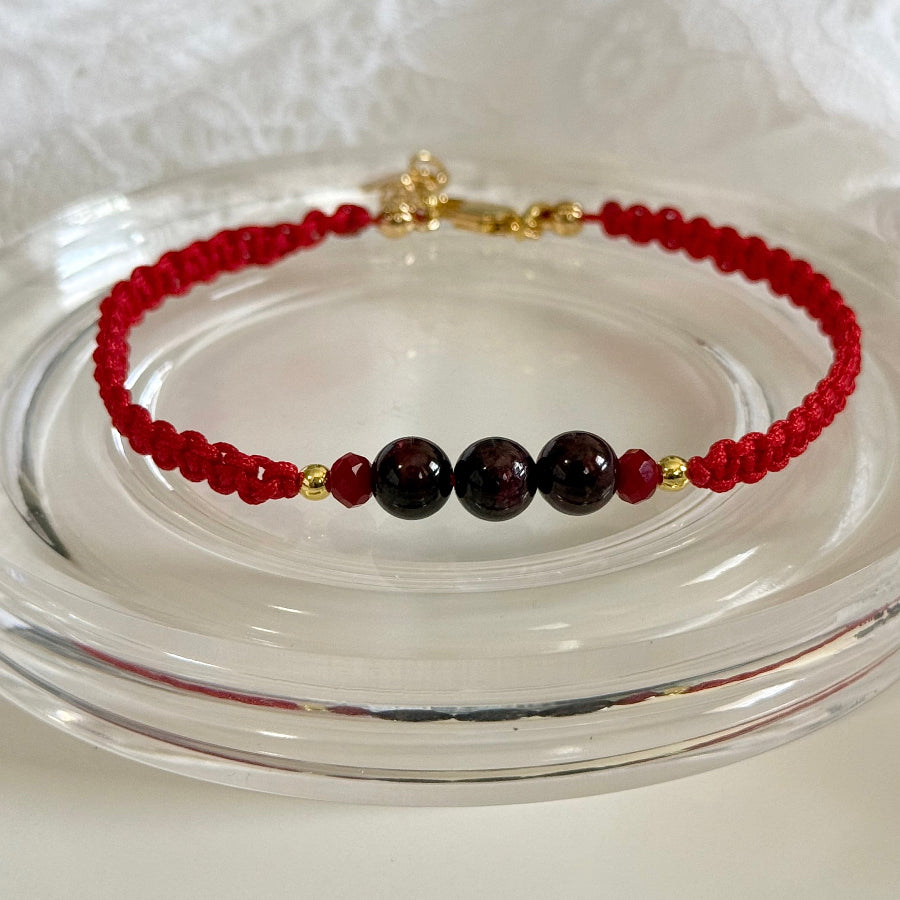 Bracelet with red and black beads on a clear glass surface