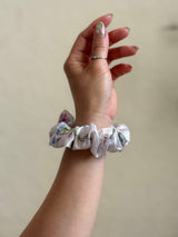ivory satin floral scrunchie with delicate blue, pink, and green flowers on a neutral base, designed for every day wear, offering a secure and stylish hold.