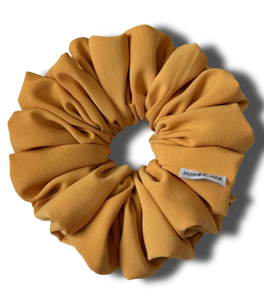 golden glow scrunchie with a brand label on a white background