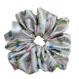 Ivory satin floral scrunchie with soft blue, pink, and green flowers on a neutral base, designed for thick and long hair, offering a secure and stylish hold.