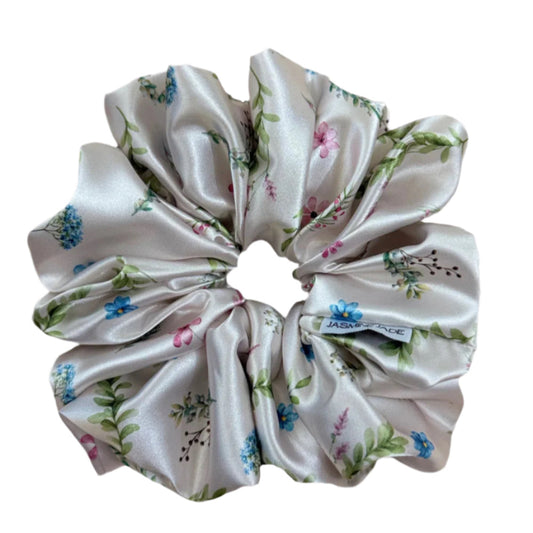 Ivory satin floral scrunchie with soft blue, pink, and green flowers on a neutral base, designed for thick and long hair, offering a secure and stylish hold.