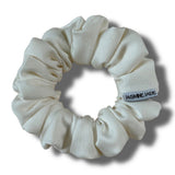White scrunchie with a brand label on a white background