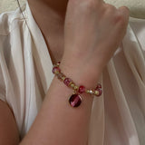 Bracelet with red and gold beads on a wrist against a neutral background