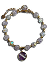 Bracelet with purple beads and a gold chain on a white background