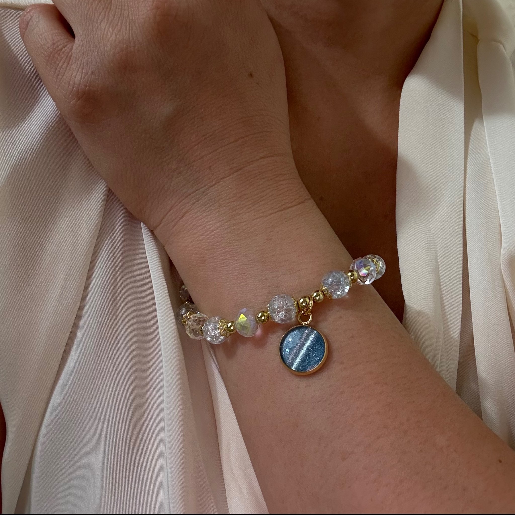 Bracelet with gemstones on a wrist against a light fabric background