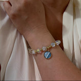 Bracelet with gemstones on a wrist against a light fabric background
