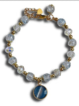 Bracelet with blue stone charm and clear beads on a white background
