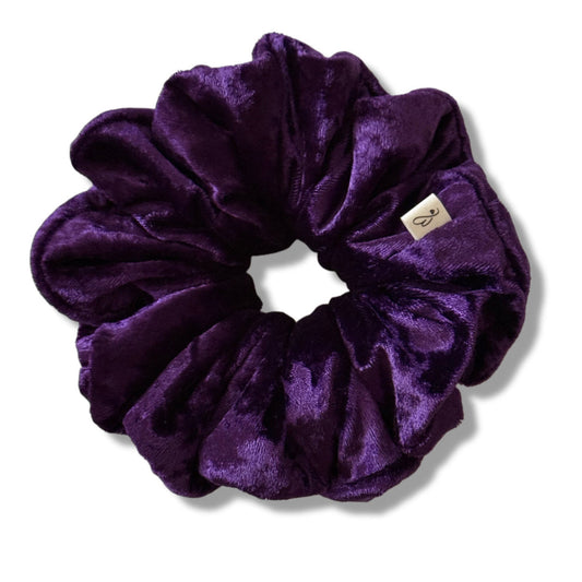 Purple velvet scrunchie with a brand label on a white background