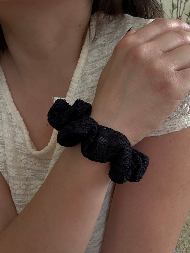 Black scrunchie on a wrist with a neutral background