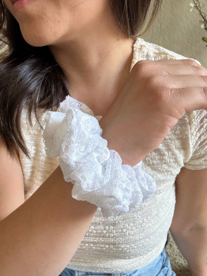 Close-up of a person wearing a white lace wristband.