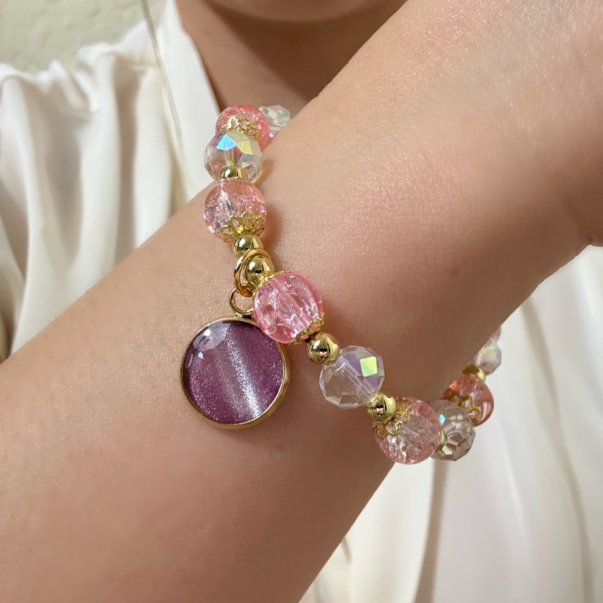 Close-up of a wrist wearing a colorful beaded bracelet with a purple round charm.