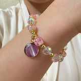 Close-up of a wrist wearing a colorful beaded bracelet with a purple round charm.