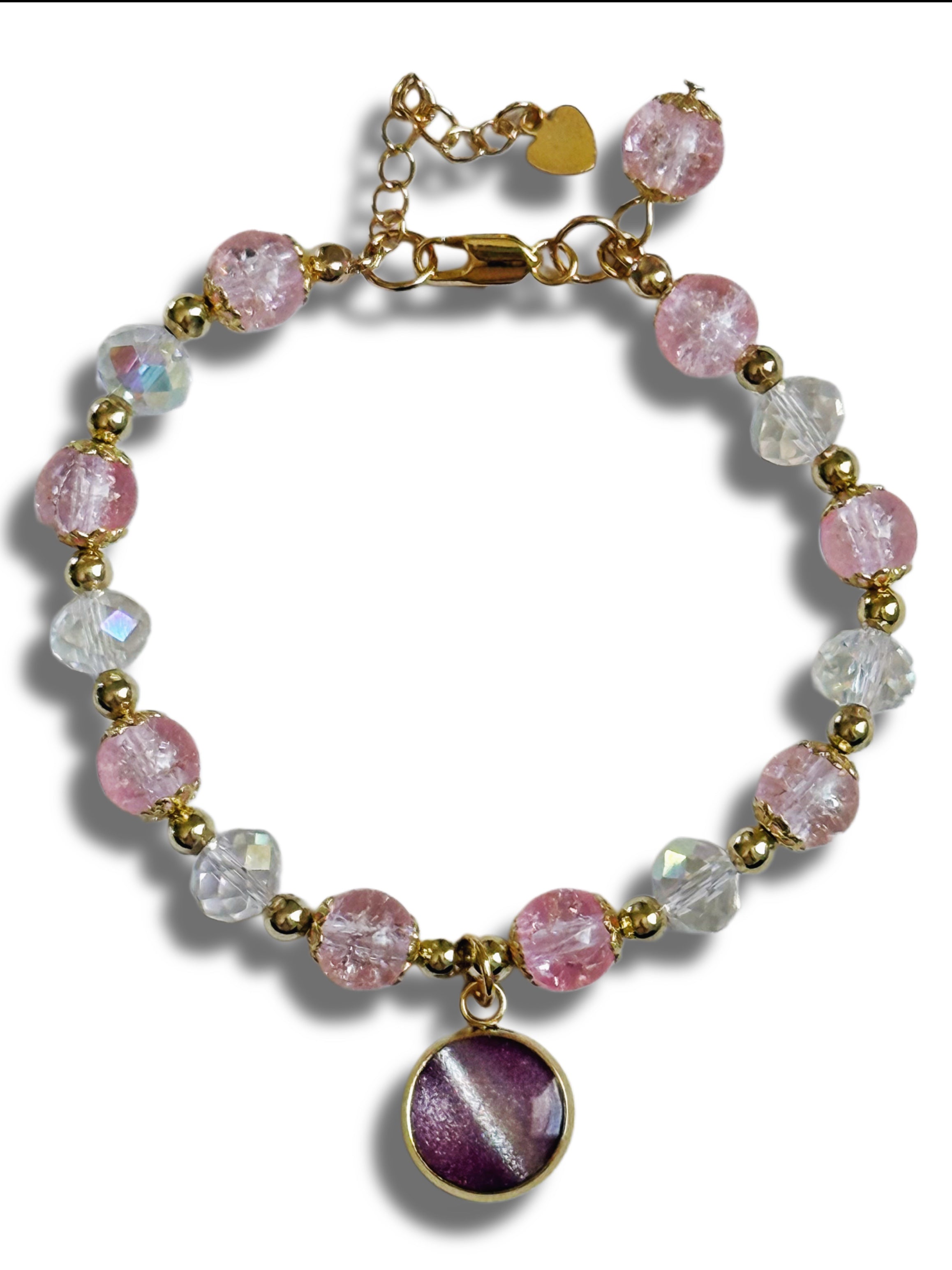 Bracelet with pink and clear beads and a purple heart charm on a white background