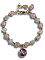 Bracelet with pink and clear beads and a purple heart charm on a white background