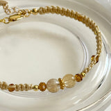 Gold and beige beaded bracelet on a clear glass surface