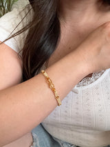 Gold bracelet on a wrist with a blurred background