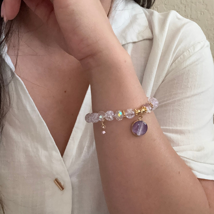 Close-up of a wrist wearing a colorful beaded bracelet on a neutral background
